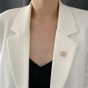 Élégante broche fleur dorée avec perles et zircon sur le revers d'un blazer blanc