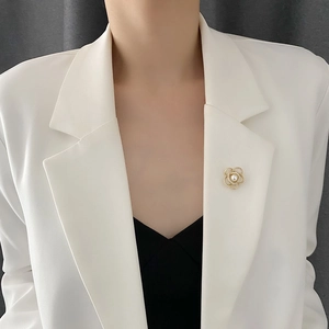 Broche camélia dorée élégante avec perle sur revers de costume blanc pour femme