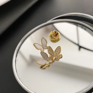 Elegant gold butterfly brooch featuring shell wings and zircons on a mirrored surface