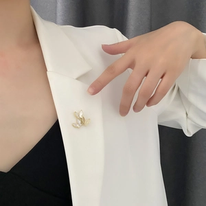 Elegant gold butterfly brooch with white shell and zircon on a white suit jacket