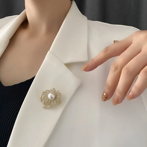 Elegant gold swirl brooch with radiant pearls and zircon crystals on a white blazer