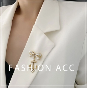 Macro detail of golden anchor and bow brooch with pearls and zircons on a white blazer