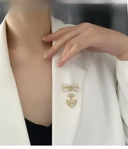 Detail view of a luxury anchor bow brooch with micro-pave zircons and pearls on white suit