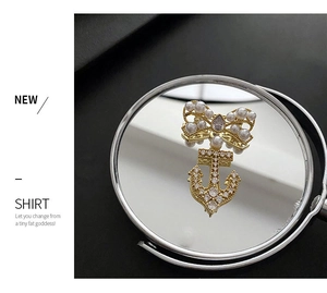 Macro shot of anchor brooch with pearl bow and clear crystals on golden metal base