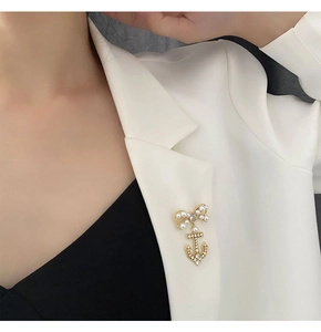 Detail of elegant bow and anchor brooch with pearls and zircons on a white suit lapel