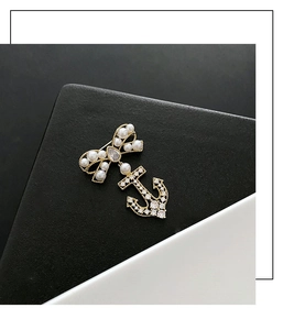 Macro detail of gold bow and anchor brooch with pearls and cubic zirconia stones