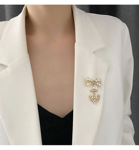Detailed view of a gold bow and anchor brooch with micro-pave zircons and white pearls