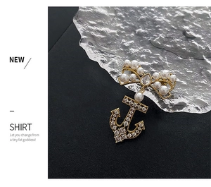 Macro view of golden bow brooch with pearls and zircon-encrusted anchor pendant