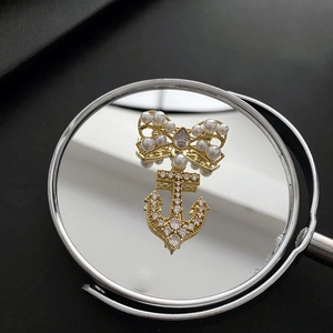 Elegant gold bow and anchor brooch with pearls and cubic zirconia on a mirror