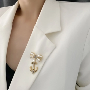 Elegant bow and anchor brooch with pearls and zircon on a white suit jacket