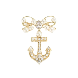 Elegant gold bow anchor brooch with pearls and cubic zirconia on a white background