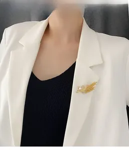 Gros plan d'une broche épi de blé dorée avec perles et strass sur un revers blanc
