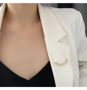 Détail d'une broche sourire dorée avec zircons épinglée sur le revers d'un tailleur