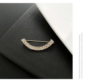 Vue détaillée d'une broche sourire dorée avec cristaux sur fond noir et blanc contrasté