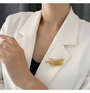Détail d'une broche en épi de blé doré avec perle sur le revers d'un blazer blanc chic