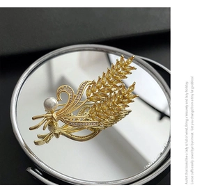Vue détaillée d'une broche épi de blé avec gemmes jaunes et perle sur miroir