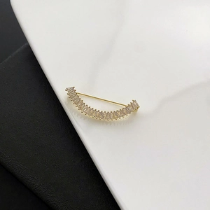 Broche élégante en forme de sourire doré avec zircons baguette sur fond noir et blanc