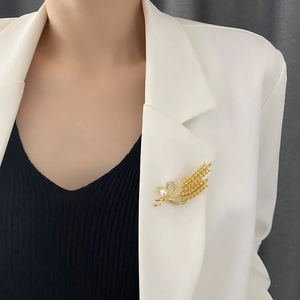Broche épi de blé dorée avec perles sur blazer blanc pour un look professionnel