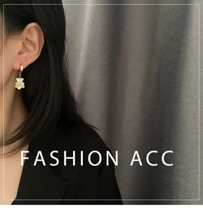 Detail of golden huggie hoop earrings with white mother-of-pearl bear pendant and heart