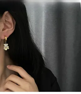 Detail of gold hoop earring with white bear charm and heart engraved with Love