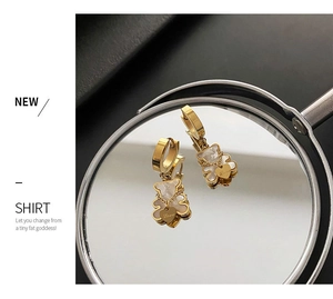 Detail of golden bear hoop earrings with white inlay and heart charm engraved Love