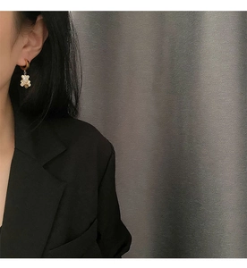 Close-up of a gold hoop earring featuring a white pearlescent bear charm on a model