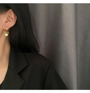 Detailaufnahme eines Models mit eleganten goldenen Schmetterlingsohrringen mit Zirkon