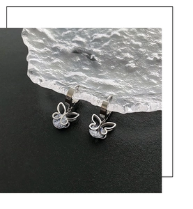 Silberne Schmetterlingsohrringe mit Zirkonia auf einem strukturierten Glastablett