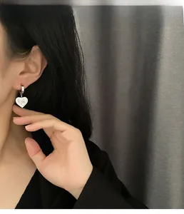 Details von Vintage-Herzohrringen mit Muscheleinlage, getragen von einem Model