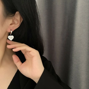 Elegante silberne Herz-Ohrringe mit Muschel-Inlay am Modell vor grauem Hintergrund