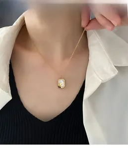 Close-up of golden rectangular mother-of-pearl rabbit pendant necklace on a model
