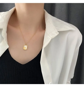 Close-up of golden titanium necklace featuring a white shell rabbit pendant on model