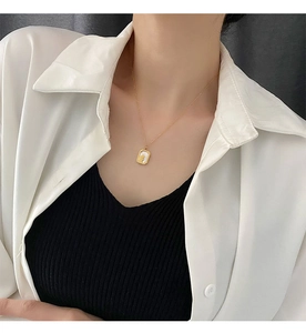 Detail of elegant gold necklace featuring a white shell pendant worn by a model