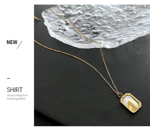 Detail of a golden rabbit pendant with white mother of pearl inlay and a rectangular frame
