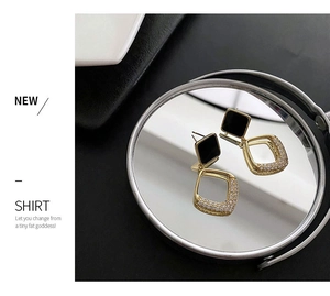 Close-up of gold geometric earrings with black square studs and micro-pave zirconia drops