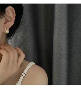 Dettaglio orecchini a fiocco dorato con perle bianche indossati dalla modella