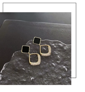 Close-up of golden square earrings with cubic zirconia inlay on frost stone