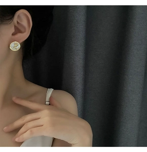 Dettaglio di un elegante orecchino a rosa con inserto in perla indossato da una modella