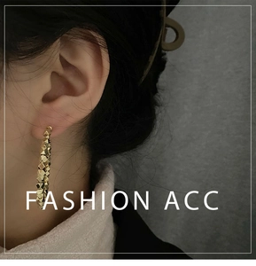 Detail of faceted gold geometric beads on dangling earrings worn by a model