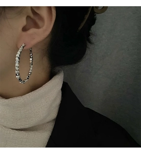 Close-up of irregular textured silver hoop earrings worn by a model in minimalist style