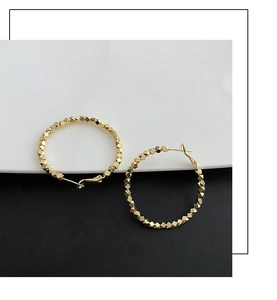 Detailed macro view of gold geometric faceted beads on round circular hoop earrings