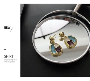 Detailed macro view of vintage gold-plated earrings with colorful enamel inlay on black