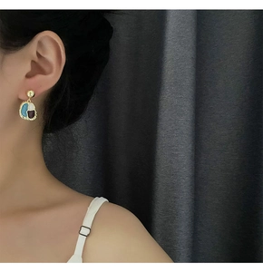 Close-up of vintage multi-color drop earrings with gold trim worn by a model