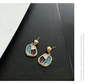 Macro detail of retro gold-plated geometric earrings with blue and purple enamel inlay