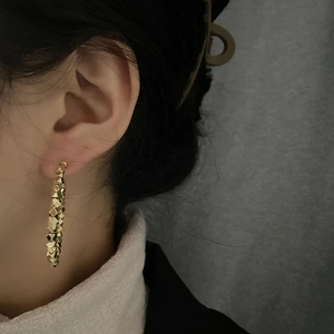 Minimalist gold hoop earrings with geometric pyramid facets on a female model
