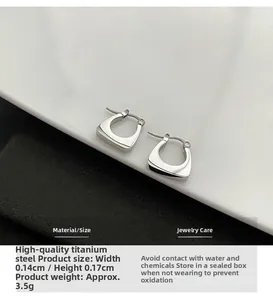 Dettaglio di orecchini a U in acciaio al titanio argento con design minimalista e altezza 1,4 cm
