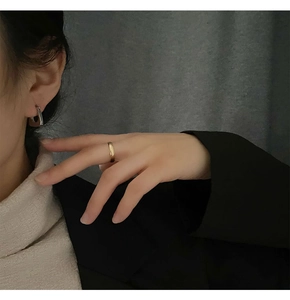Dettaglio di un anello dorato e orecchino a cerchio in argento su una modella