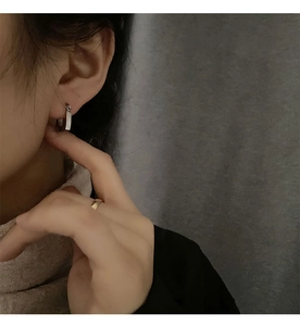 Primo piano di orecchini a cerchio minimalisti in argento e anello d'oro su sfondo in tessuto