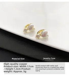 Détail d'une boucle d'oreille cœur dorée avec zircon et perle de 1,1x1,3 cm