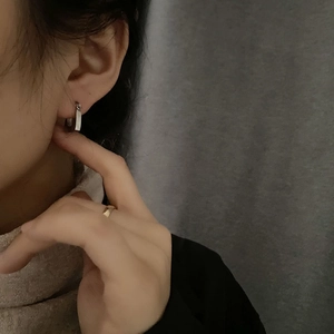 Orecchini a cerchio in acciaio al titanio e anello d'oro su modella per un look trendy
